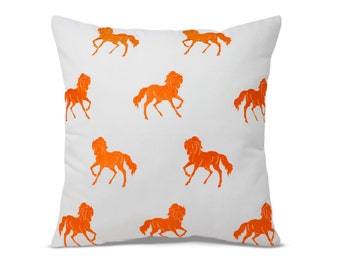 May include: Orange horse silhouettes are repeated on a white square throw pillow. The pillow is made of a soft, white fabric.