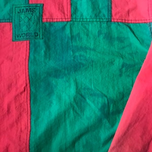 May include: A red and green jacket with a black patch that says "JAMS WORLD" on it.
