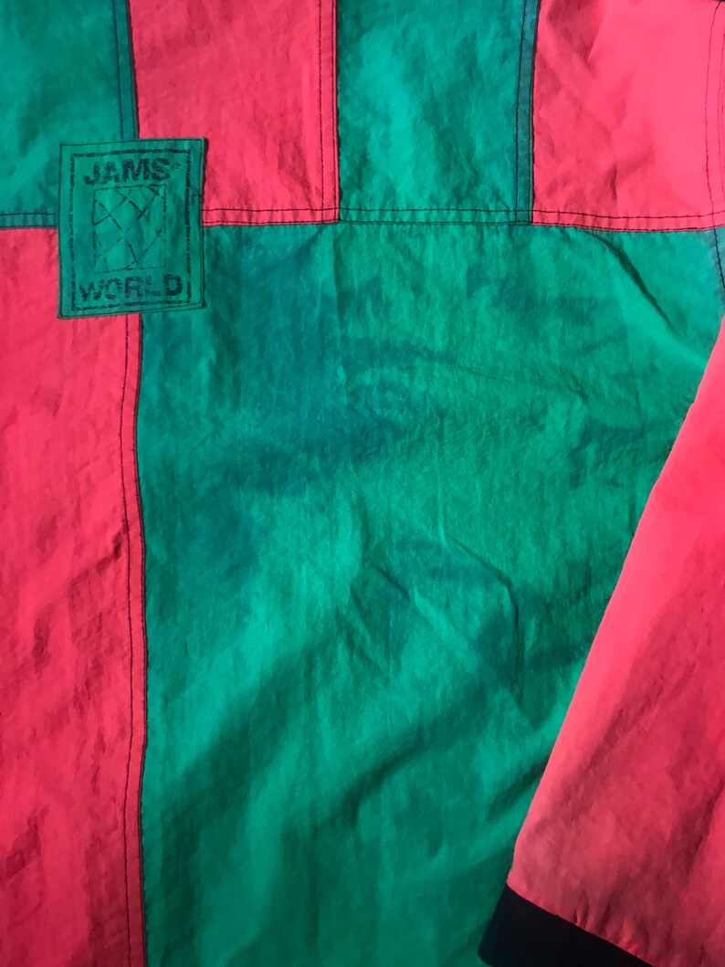 May include: A red and green jacket with a black patch that says "JAMS WORLD" on it.