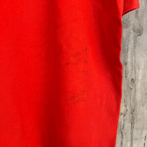 K&ouml;nnte beinhalten: Ein einfarbiges rotes T-Shirt mit kurzen &Auml;rmeln. Das Shirt ist aus einem weichen, bequemen Material.