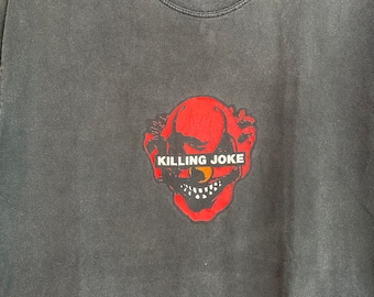 May include: Dark grey t-shirt with a red and black clown face graphic and the text "KILLING JOKE". The shirt is displayed on a black hanger.