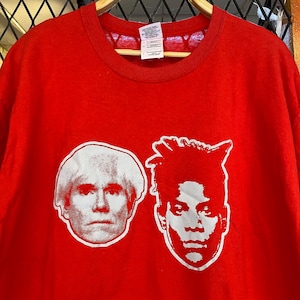 K&ouml;nnte beinhalten: Rotes T-Shirt mit einem wei&szlig;en Grafikdruck der Gesichter von Andy Warhol und Jean-Michel Basquiat.