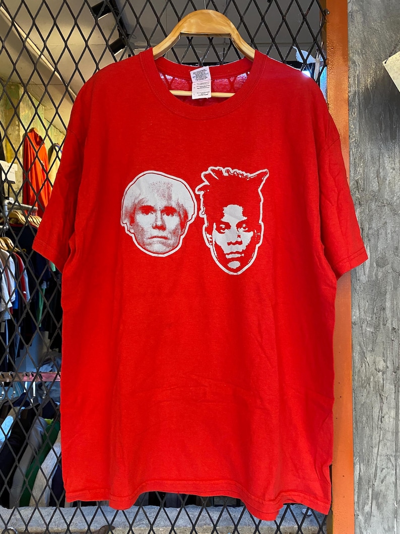 K&ouml;nnte beinhalten: Rotes T-Shirt mit einem wei&szlig;en Aufdruck der Gesichter von Andy Warhol und Jean-Michel Basquiat.