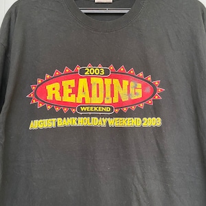 May include: Black t-shirt with a red and yellow graphic that says "2003 Reading Weekend August Bank Holiday Weekend 2003"