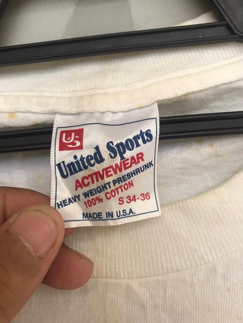 May include: White tag with blue text that reads "United Sports Activewear Heavy Weight Preshrunk 100% Cotton S 34-36 Made in U.S.A."