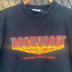 May include: Black t-shirt featuring a red and yellow "Backdraft" graphic with flames. The text "Universal Studios Japan" is printed below the graphic.