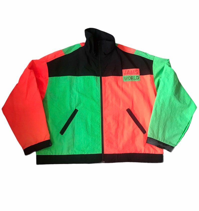 May include: A black, green, and orange color block jacket with a zipper closure. The jacket has a black collar and a black band around the bottom. The text "JAMS WORLD" is printed on the front of the jacket.