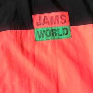 May include: A black and red jacket with a green patch that says "JAMS WORLD" in black lettering.