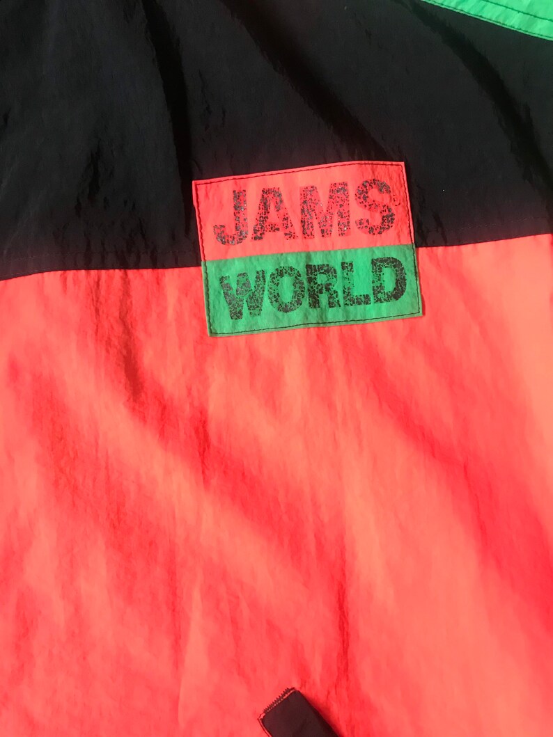 May include: A black and red jacket with a green patch that says "JAMS WORLD" in black lettering.