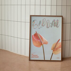 May include: A framed poster with the word "BLOOM" in iridescent letters and two pink and orange anthurium flowers. The poster has the text "Flower portrait" and "(2/5)" printed on it.
