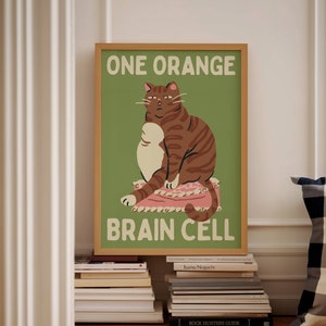 May include: A green and brown poster with a cartoon cat sitting on a pink pillow. The poster says "One Orange Brain Cell" in white text.