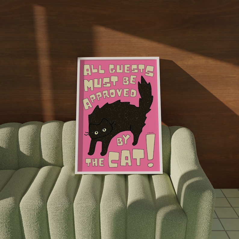 May include: A pink and white sign with a black cat illustration and the text "All guests must be approved by the cat!"