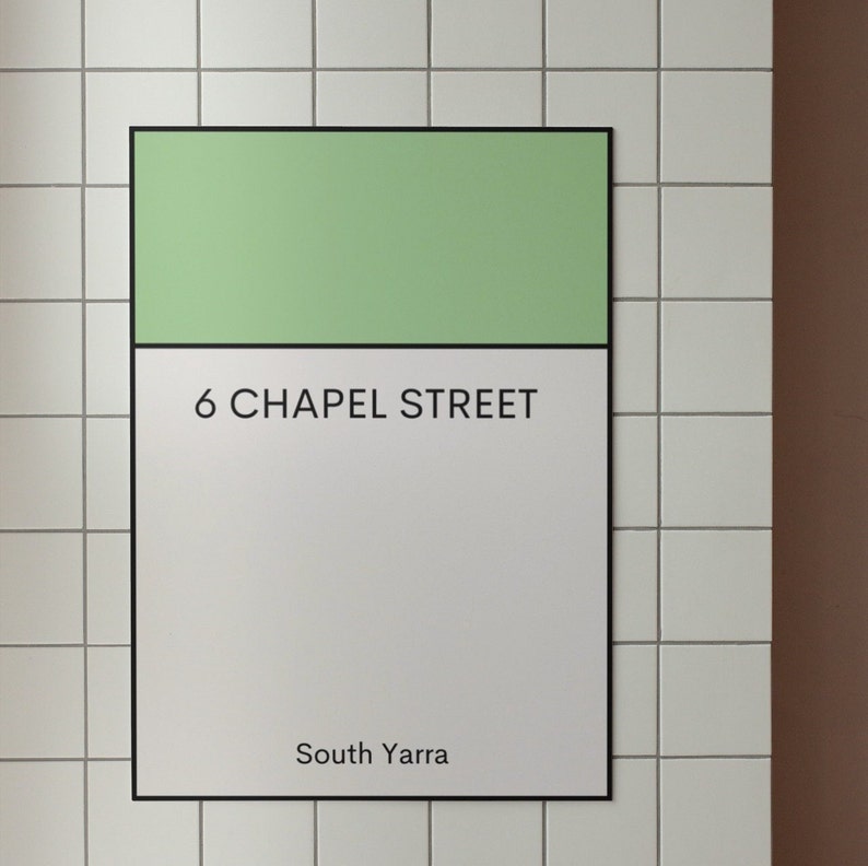 May include: A white sign with black text on a tiled wall. The sign reads "6 Chapel Street, South Yarra". The top portion of the sign is a light green color.