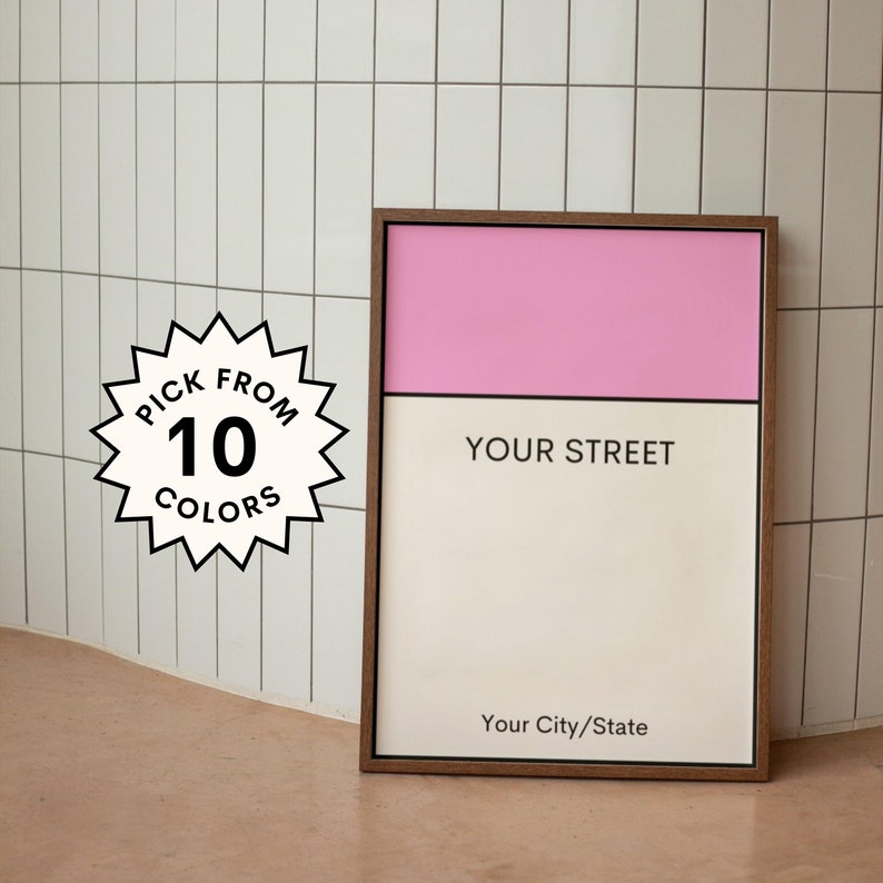 May include: A framed print with a pink and white color scheme. The print has the text "YOUR STREET" and "Your City/State". The print is surrounded by a brown frame. A starburst sticker with the text "PICK FROM 10 COLORS" is in the lower left corner of the image.