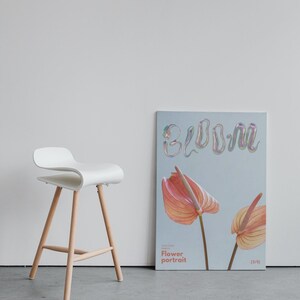 May include: A poster with the word "bloom" in iridescent letters, with two pink and orange anthurium flowers on a light blue background. The poster also includes the text "Flower portrait" and "(2/5)".