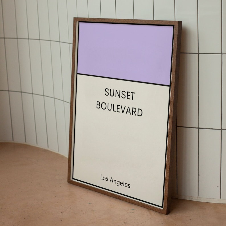 May include: A framed print with a light purple top section and a white bottom section. The text "SUNSET BOULEVARD Los Angeles" is printed in black on the white section.