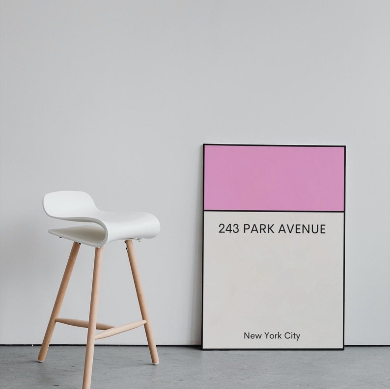 May include: A white chair with wooden legs sits in front of a pink and white poster with the text "243 Park Avenue, New York City".