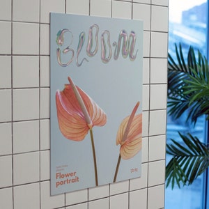 May include: A poster with the word "bloom" in a holographic font. The poster features two pink and orange anthurium flowers. The text "Funky Friday Designs" and "Flower portrait" are at the bottom of the poster. The number "(2/5)" is in the bottom right corner.