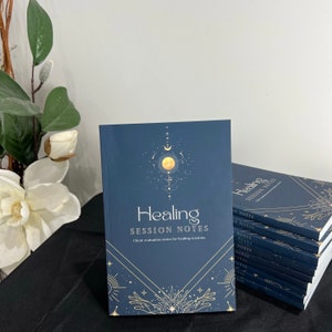 May include: A blue notebook with gold lettering that says "Healing Session Notes" and a gold celestial design. Client evaluation notes for healing sessions.