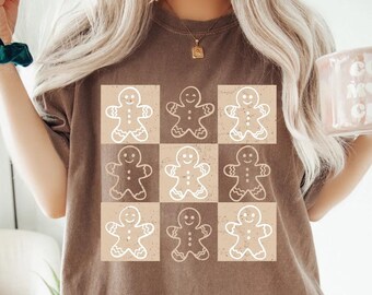 May include: Espresso-colored t-shirt featuring a grid of gingerbread men in white and tan. The shirt has a relaxed fit and is made of a soft material. The word "ESPRESSO" is printed in a white font at the bottom right corner.