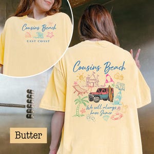 Op de afbeelding: Boterkleurig T-shirt met de tekst "Cousins Beach" en strandthema-afbeeldingen. De voorkant van het shirt heeft de tekst "Cousins Beach" en "East Coast". De achterkant van het shirt heeft een jeep, surfplank en andere zomerse illustraties.