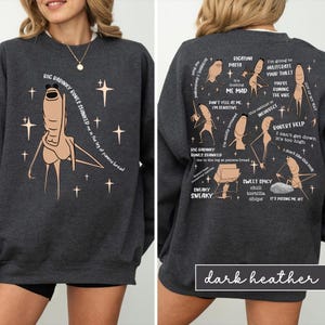 May include: Dark heather gray sweatshirt with a cartoon illustration of a character with the text "RIC RADINKY BONES SHANKED" and other phrases. The back of the sweatshirt has more cartoon figures and phrases.