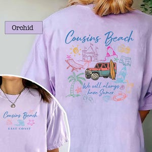Op de afbeelding: Orchidee-kleurig T-shirt met een strandthema. Het ontwerp bevat een jeep, een surfplank en de woorden "Cousins Beach" en "We will always have Summer". Een kleinere versie van het ontwerp staat op de voorkant.