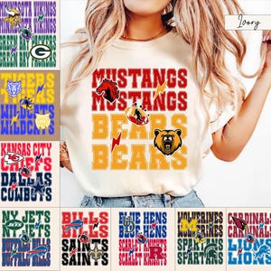 May include: An ivory t-shirt featuring the red text MUSTANGS and yellow text BEARS, accompanied by a red horse head graphic, a football, a yellow lightning bolt, and a brown bear head graphic. The design includes layered typography and sports icons.