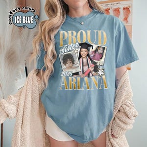 Puede incluir: Camiseta azul hielo con las palabras "PROUD Sister" y el nombre "ARIANA" en letras doradas. La camiseta presenta tres fotos enmarcadas de una persona, con el a&ntilde;o "2026" debajo de una foto. Las palabras "comfort colors" y "ICE BLUE" est&aacute;n en un c&iacute;rculo.