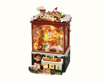 May include: A festive Christmas-themed decorative box with a red exterior, featuring a lit interior scene with a snowman, Christmas tree, and other holiday figures. The top reads "Merry Christmas".