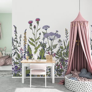 May include: A white wall with a floral mural featuring a variety of green plants and flowers in shades of pink, purple, and yellow. A pink canopy bed with gold stars hangs in the corner of the room. A white desk with a pink chair sits in front of the mural.