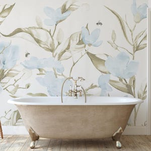 May include: A vintage-style bathtub with brass fixtures and claw feet is the focal point of a bathroom. The wall behind the tub features a floral mural with blue and green watercolor flowers. A small wooden stool and a shelf with towels and toiletries complete the spa-like setting.