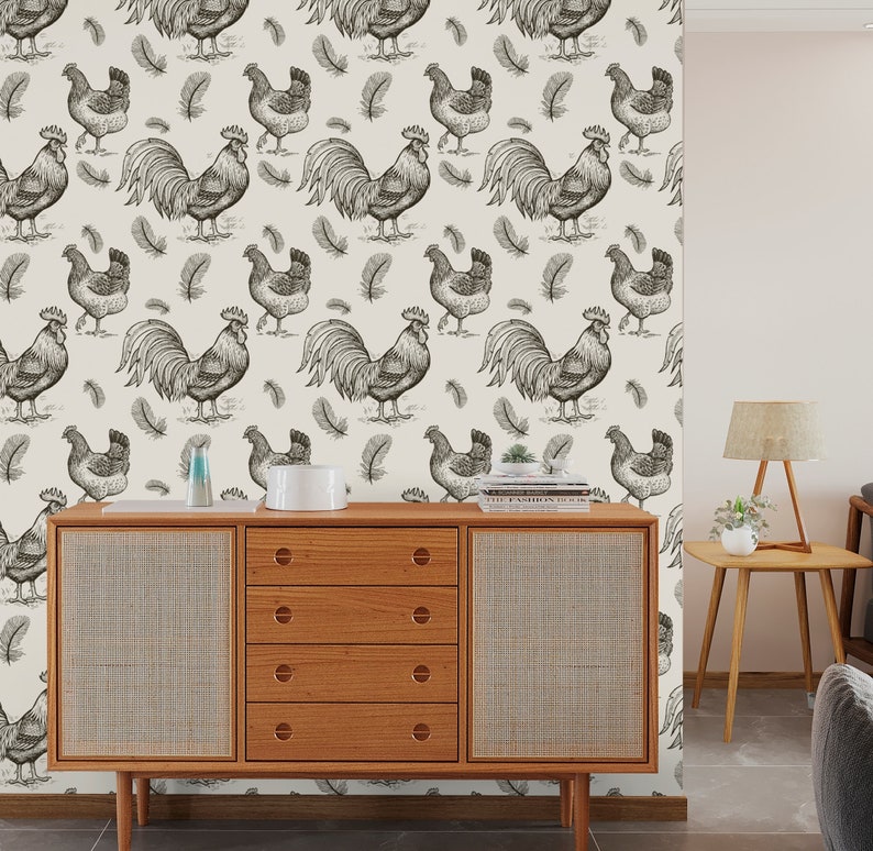 May include: A white background with a repeating pattern of black and white illustrations of roosters and feathers. The pattern is on a wall behind a wooden dresser with five drawers.