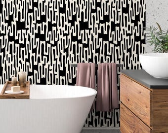 May include: A modern bathroom with a black and white patterned wallpaper, a white bathtub, a wooden vanity with drawers, and a towel rack with two towels.