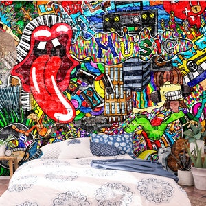 May include: A vibrant graffiti mural featuring the iconic Rolling Stones tongue logo, musical elements, and the word "MUSIC". The artwork is displayed on a brick wall, with a bed and decorative items in the foreground. The color palette includes red, blue, yellow, and green.