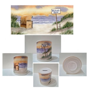 Può includere: Salvadanaio in ceramica bianca con un'immagine ad acquerello di una scena di spiaggia. L'immagine include una sedia da spiaggia, un cartello che dice "Urlaubs-kasse" e una spiaggia sabbiosa con acqua blu sullo sfondo.