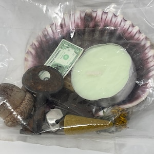 May include: A clear plastic bag containing a variety of items, including a seashell, a candle, a key, a bell, a small wooden stick, a brown acorn, and a one dollar bill.