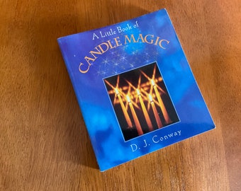 May include: A blue book titled "A Little Book of Candle Magic" by D.J. Conway. The cover features a photo of lit candles with a blue and white star pattern.