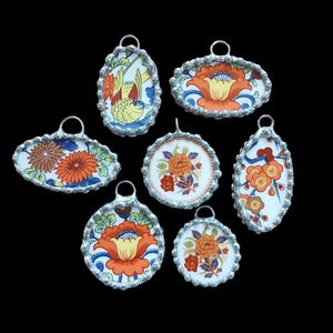 May include: Seven oval and round pendants with silver-toned metal frames and colorful floral and bird designs on white porcelain.