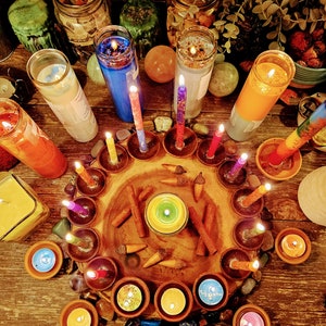 May include: A wooden tray with a variety of candles arranged in a circle. The candles are in different colors, including red, blue, green, and yellow. There are also some cinnamon sticks and other decorative items on the tray.
