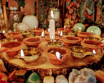 May include: A wooden tray with a variety of small, lit candles and tealight holders. The candles are arranged in a circle around a larger white candle. There are also several small, colorful stones scattered around the tray.