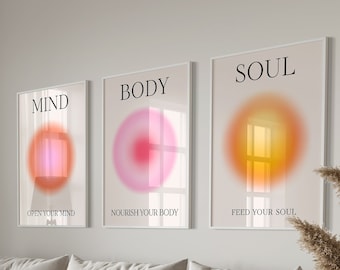 Peut inclure: Trois affiches minimalistes avec des cercles abstraits dans des tons de rose, rouge et jaune. Les affiches sont encadrées en blanc et portent les mots "MIND", "BODY" et "SOUL" en texte noir. Les affiches sont accrochées à un mur blanc dans un salon.