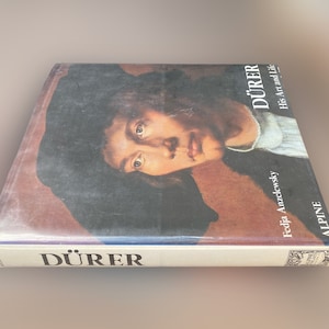May include: A book titled "Dürer: His Art and Life" by Fedja Anzelewsky. The book cover features a painting of a man with dark hair and a black hat. The book is published by Alpine.