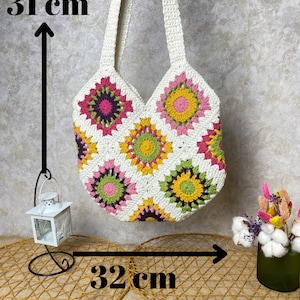 May include: White crochet tote bag with a floral pattern in pink, yellow, and green. The bag measures 31 inches tall and 32 inches wide.