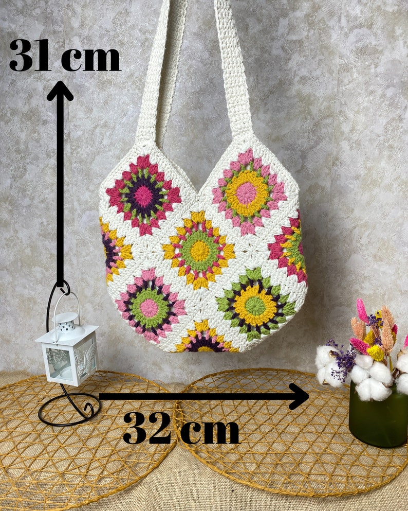 May include: White crochet tote bag with a floral pattern in pink, yellow, and green. The bag measures 31 inches tall and 32 inches wide.