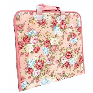 May include: A floral patterned art portfolio case with a handle. The case features a peach background with a pattern of red, white, and blue flowers. The edges and handle are a solid peach colour.