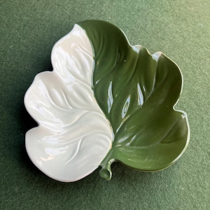 Puede incluir: Un plato de cerámica con forma de hoja con un esmalte blanco y verde. El plato está dividido por la mitad, con un lado blanco y el otro verde.