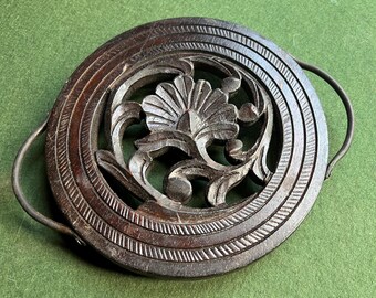 Quirky wooden trivet. Vintage carved wood round trivet with metal handles. 3 footed hand carved trivet with floral centre.
