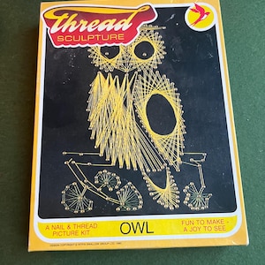 May include: A boxed nail and thread picture kit featuring an owl design. The kit includes a black background with a yellow thread owl, and the text "Thread Sculpture" and "Owl". The box is yellow and black.