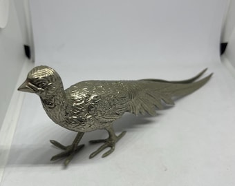 May include: A silver metal figurine of a pheasant with detailed feathers and a long tail.